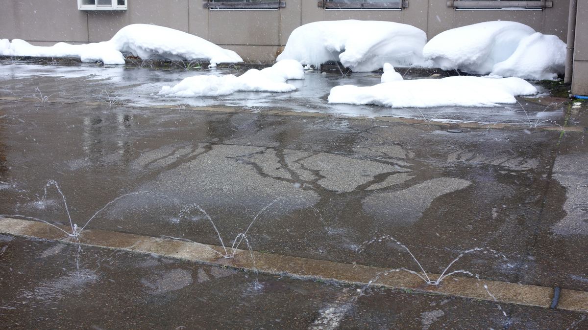 雪が積もり、消雪パイプで路面を出している冬の新潟の道